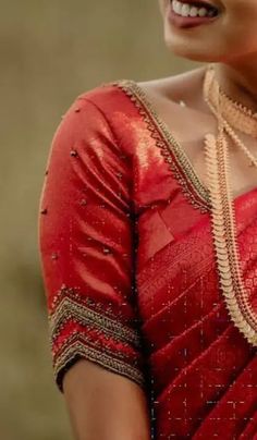 a woman wearing a red sari and gold necklace