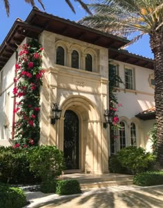 a large white house with pink flowers on it's front door and palm trees