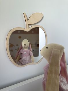 a stuffed animal is in front of an apple shaped mirror with the reflection of a bunny