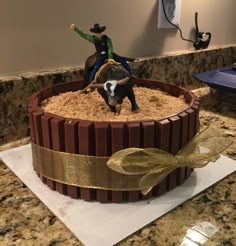 a cake with a cowboy riding a horse on top of sand in the shape of a barrel