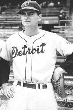 an old black and white photo of a baseball player in uniform with his hands on his hips