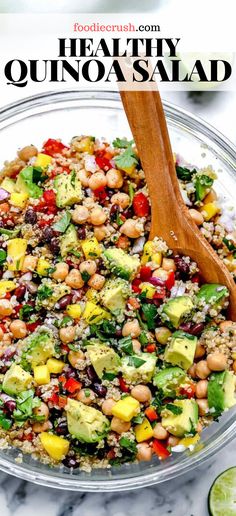 healthy quinoa salad in a glass bowl with wooden spoon