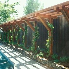 a car parked in front of a wooden structure with vines growing on it's sides