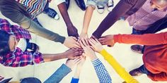 a group of people standing in a circle with their hands on top of each other