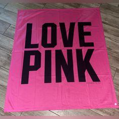 a pink towel with the words love pink printed on it in black font, sitting on a wooden floor