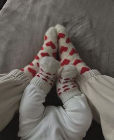 a baby laying on top of a bed wearing white pants and red socks with hearts