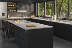 a modern kitchen with an island countertop and bar stools in front of large windows