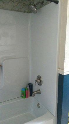 a bathroom with a bathtub, shower head and toilet paper holder on the wall