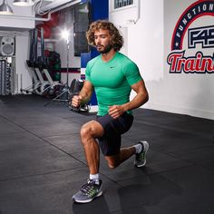 a man is squatting in the gym with his feet on the ground and one hand behind him