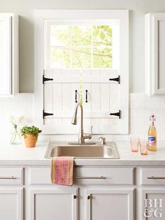 a kitchen with white cabinets and an open window above the sink is seen in this image