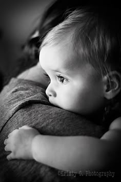 a black and white photo of a baby holding it's mother in her arms