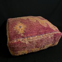 a red and yellow cushion sitting on top of a black surface