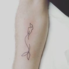 a woman's arm with a tattoo on it that has a line drawing of a mermaid