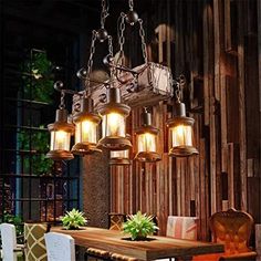 a chandelier hanging over a dining room table with chairs and potted plants