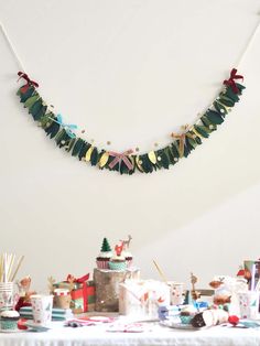 a table topped with lots of cake and cupcakes next to a wall hanging