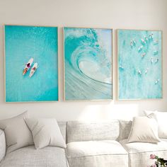 three paintings hang on the wall above a couch