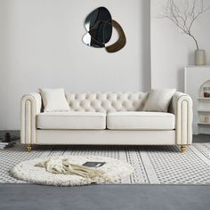 a white couch sitting on top of a rug in a living room next to a wall mounted clock