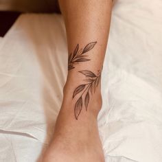 a woman's foot with a leaf tattoo on her left ankle and the bottom part of her leg