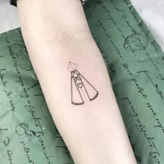 a woman's arm with a small tattoo of a dress and umbrella on it