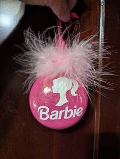 a pink rock with a white feather on it and the word barbie painted on it