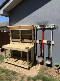 a wooden bench sitting in the middle of a yard next to a garden tool rack