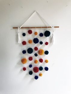 a multicolored wall hanging with tassels and pom - poms