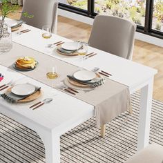 a dining room table set with plates and silverware on it, next to a window