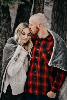 a man and woman standing next to each other in the woods