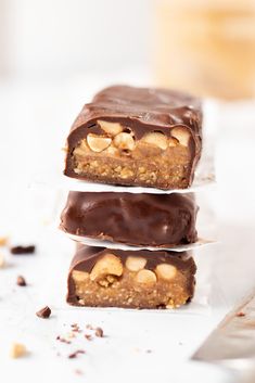 three pieces of chocolate peanut butter bars stacked on top of each other with nuts in the middle