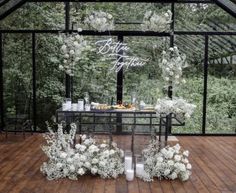 a table with white flowers and candles on it in front of a glass wall that says happy new year