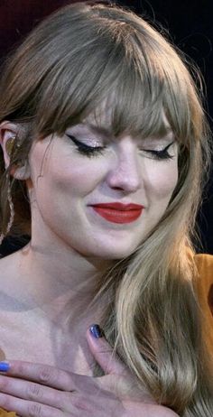 a close up of a person holding a cell phone near her face and wearing red lipstick