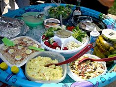 a table filled with lots of food on top of a blue tray covered in plastic