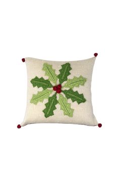 a white pillow with green and red holly decorations on the front, sitting on a white surface