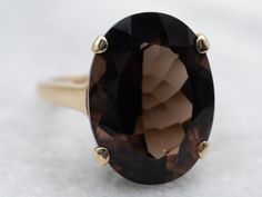 This ring is crafted in gleaming yellow gold and set with a stunning smoky quartz in the center of a classic solitaire design. The smooth lines and timeless look offer a classic and elegant appeal, perfect for any occasion.Metal: 10K Yellow GoldGem: Smoky Quartz 8.26 CaratsGem Measurements: 12.0 x 16.2 mm, OvalRing Size: 5.25Marks: "J-10K-L" Stamped on the inside band Timeless Polished Topaz Ring, Classic Smoky Quartz Rings For Formal Occasions, Classic Oval Brown Ring, Classic 14k Gold Brown Ring, Classic Brown Oval Ring, Classic Formal Smoky Quartz Rings, Elegant Solitaire Topaz Ring For Formal Occasions, Formal Timeless 14k Gold Topaz Ring, Elegant Formal Solitaire Topaz Ring