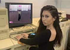 a woman sitting in front of a computer with a keyboard and monitor on her desk