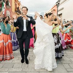 a bride and groom are walking down the street with their arms in the air as they dance