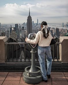 a woman standing on top of a tall building looking at the cityscape in the distance