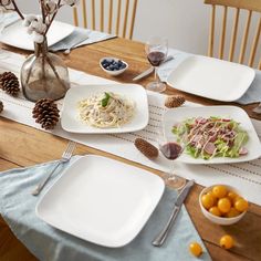 the table is set with plates, silverware, and oranges on it for dinner