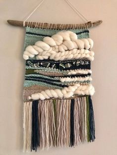 a wall hanging made out of different types of yarn and cottons on a wooden stick