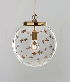 a clear glass globe with gold stars on it and a light bulb hanging from the ceiling