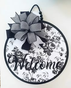 a black and white welcome sign with a bow on it's front door hanger