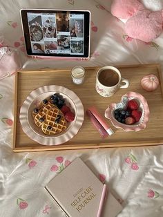 a tray that has some food on it and a laptop next to it with a book