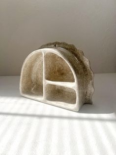 a small white object sitting on top of a bed next to a wall and window