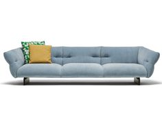 a blue couch with two yellow pillows on it's back and one green pillow