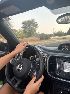 a woman driving a car with her hands on the steering wheel