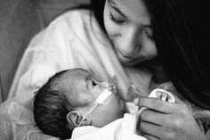 a black and white photo of a woman holding a baby in her arms while she is nursing