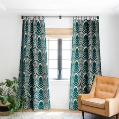 a living room with a chair, window curtain and potted plant in the corner