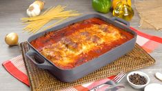 a casserole dish with meat and cheese in it on a table next to some vegetables