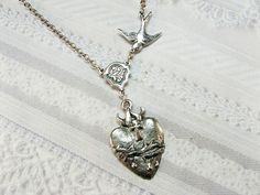 A sterling plated sparrow carries a vintage inspired rosary connector that holds a beautifully detailed sacred heart charm.   Pendant measures approximately one inch and necklace measures approximately 18 inches. Compass Necklace Silver, Sacred Jewelry, Silver Rings With Stones, Catholic Jewelry, Dope Jewelry, Silver Heart Necklace, Jewelry Lookbook, Dream Jewelry, Sacred Heart