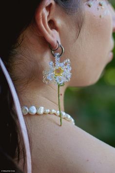 a close up of a person wearing some kind of earring with flowers on it